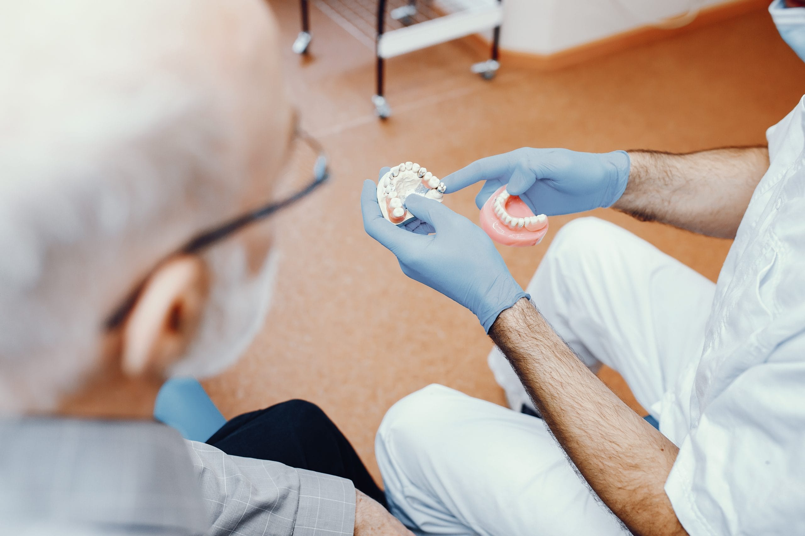 Old man sitting in the dentist's office discussing dental implants with the dentist, reading